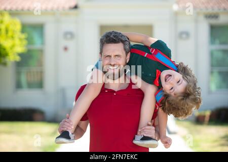 Parent supports and motivates son. Father giving son piggyback ride after come back from school. Stock Photo