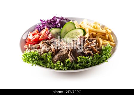 Isolated delicious Turkish veal kebab served on the white plate with fresh green letuce, juicy tomatoes, cabbage, cucumber and crispy and salty french Stock Photo