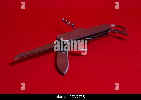 Swiss multifunctional knife on a red background. Stock Photo