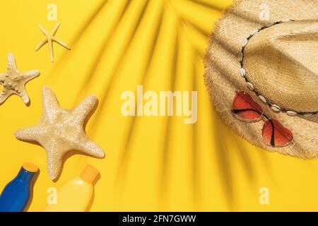 Flat composition with beach holiday accessories on yellow background and palm leaf shadow, summer background. Stock Photo