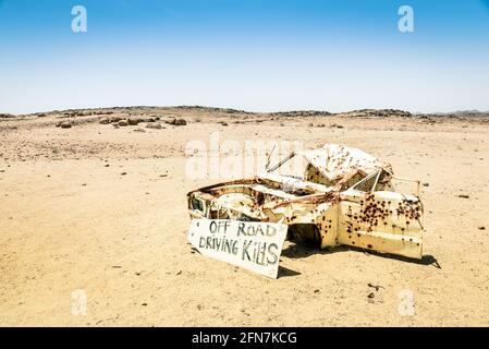 Car wreck in the namibian desert - Danger sign about driving off roads Stock Photo