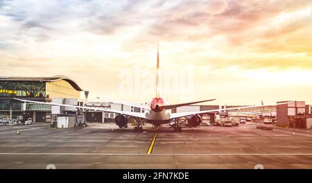 Back view of modern airplane at terminal gate ready for takeoff on runway - International airport with cloudy sky - Travel and wanderlust concept Stock Photo