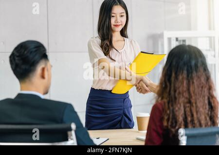 Young Asian woman graduate hand shake with two manager to welcome before start to job interview with positive motion in meeting room,Business Hiring n Stock Photo