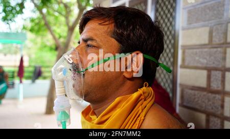 Man suffering from Covid 19 disease. Man admitted in hospital and inhaling emergency oxygen with canula mask. Stock Photo