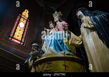 Statue of Virgin Mary enthroned with baby Jesus in her arms, crown on their heads and rosary in hands. Stained glass window in Gothic style Stock Photo