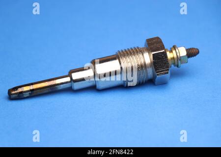Glow plug for diesel engine which is auto spare part that is necessary for engine to start by heating the internal combustion part on blue background Stock Photo