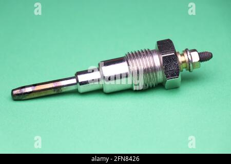 Glow plug for diesel engine which is auto spare part that is necessary for engine to start by heating the internal combustion part on green background Stock Photo
