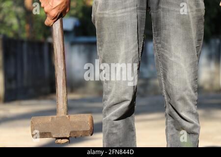 Man holding old and rusty hammer with wood handle on one hand. Hammer which is iron tool for construction purposes Stock Photo