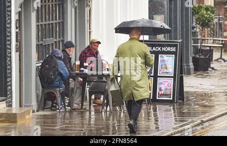 Brighton UK 15th May 2021 - These drinkers don't let the rain spoil their day in Brighton as wet weather sweeps across most parts of Britain today : Credit Simon Dack / Alamy Live News - Editorial Use Only Stock Photo