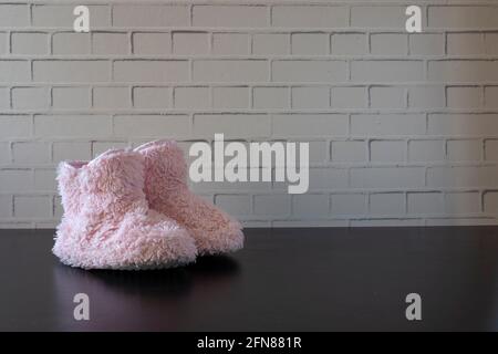 pink fluffy slippers with white tup in front of the wall and on a black background Stock Photo