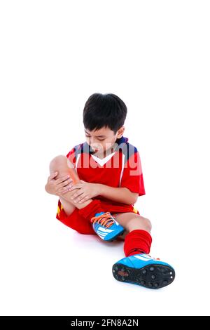 Sports injure. Youth asian soccer player in red uniform injured at shin. Isolated on white background. Studio shot. Full body. Stock Photo