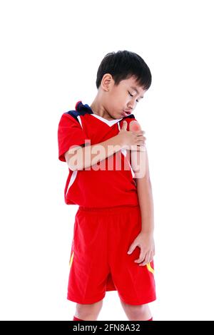 Sports injure. Youth asian soccer player in red uniform injured at  shoulder. Isolated on white background. Studio shot. Stock Photo