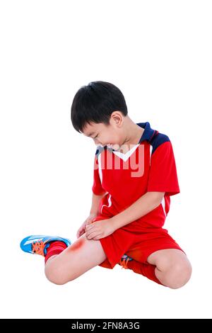 Sports injure. Youth asian soccer player in red uniform injured at thigh. Isolated on white background with copyspace. Studio shot. Stock Photo