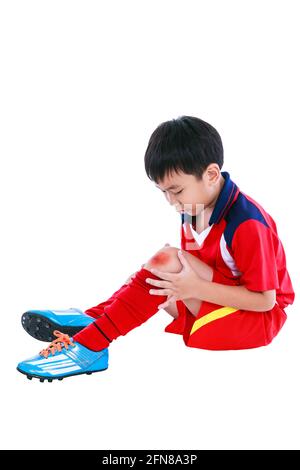 Sports injure. Youth asian soccer player in red uniform injured at knee. Isolated on white background. Studio shot. Full body. Stock Photo