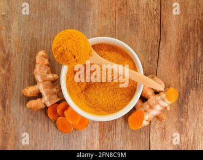 Top view of Turmeric roots with turmeric powder on wooden background Stock Photo