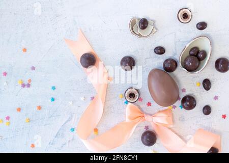 eggs-shaped candies and round candies with peach bow and ribbon on a white background. top view Stock Photo