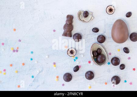 chocolate eggs and round candies with chocolate rabbit and ribbon on a white background. top view Stock Photo
