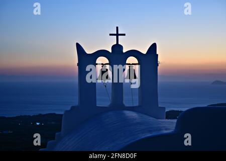Sunset seascape through a campanile of a whitewashed Greek Orthodox church with panoramic view of the Aegean Sea in Santorini island, Cyclades Greece Stock Photo
