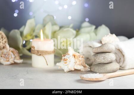 massage stones, seashell, burning candles, rolled towels, sea salt, flowers, abstract lights. Spa resort therapy composition Stock Photo