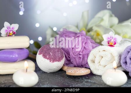 spa resort therapy composition. Stones, burning candles, orchid flowers, towel, abstract lights on black textured background. Stock Photo
