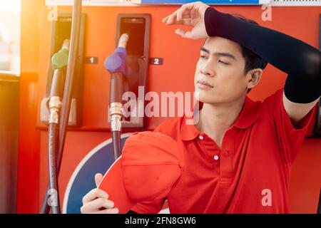 Tired staff worker working at gas station feel stressed from no customer and hot weather in summer season Stock Photo