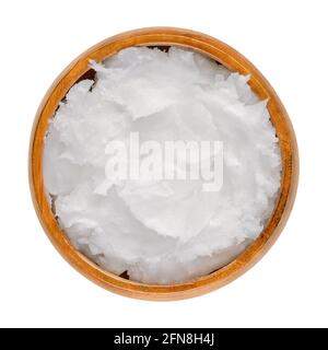 Coconut oil in a wooden bowl. Unrefined coconut butter, an edible oil, derived from the wick, meat, and milk of the coconut palm fruit. Stock Photo