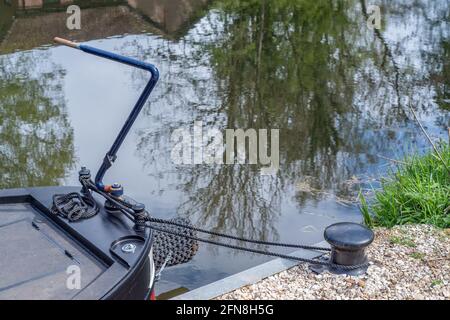 Stern of a moored canal boat with woven rope bumper and blue metal tiller. Stock Photo