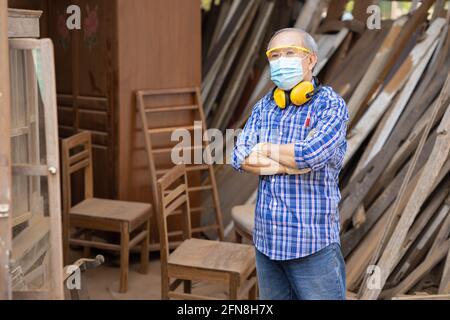 Portrait of elder wood worker hobby for good retirement, Asian male mature professional master of wood craft furniture wooden maker man. Stock Photo