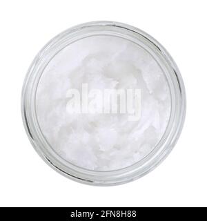 Coconut oil in a glass jar. Unrefined coconut butter, an edible oil, derived from the wick, meat, and milk of the coconut palm fruit. White solid fat. Stock Photo