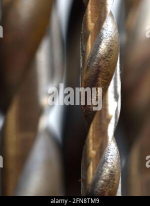 An extreme close up of a single drill bit surrounded by other drill bits that are out of focus. Stock Photo