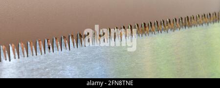 An oblique close up image of the blade of a pull saw showing its teeth. Stock Photo