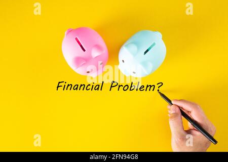 A hand writes the words FINANCIAL PROBLEM on the yellow background. Business and finance concept Stock Photo