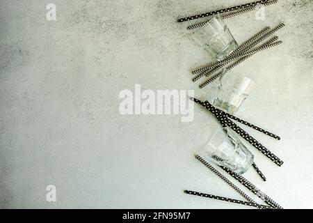 Variety of black and white stripped and dots paper stripped cocktail straws and glasses on concrete background Stock Photo