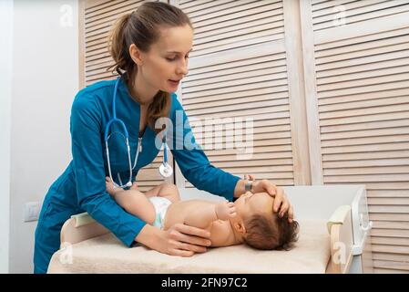 Portrait of a baby who is being examined by a doctor and listening with a stethoscope indoors Stock Photo