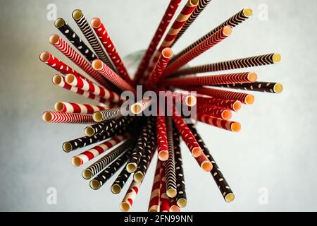 Variety of red and black and white stripped and dots paper stripped cocktail straws and glasses on concrete background Stock Photo