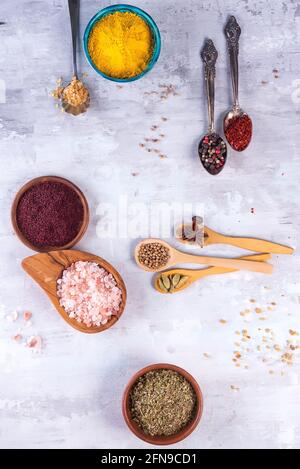 Dried herb and spice food in metal and olive wood spoons and bowls on stone background. Stock Photo