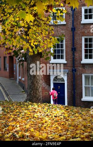 A woman wearing a pink jacket calls in at a Georgian terraced house on College Hill, Shrewsbury, Shriopshire Stock Photo