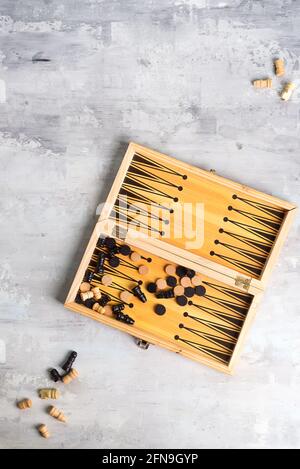 backgammon dice and pieces with a pair of chess pieces on the stone background, flat lay Stock Photo