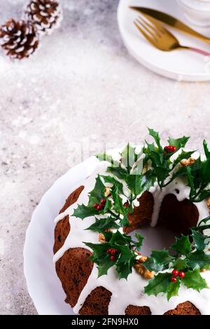 Christmas homebaked dark chocolate bundt cake decorated with holly berry branches on stone Stock Photo