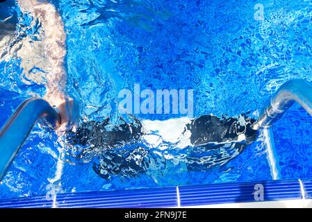 Female's hand holding a handrail in a swimming pool Stock Photo