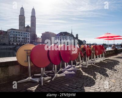 Outside cafe tables are folded away in front of a restaurant that is closed due to Covid lockdown at downtown Zurich on a sunny spring day. Stock Photo