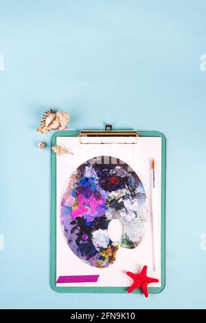 palette with old paint strokes on clipboard with seashells Stock Photo