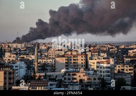 Gaza City, Palestinian Territories. 14th May, 2021. Thick smoke rises above buildings in Gaza City, following several Israeli airstrikes, amid the escalating flare-up of Israeli-Palestinian violence. Credit: Mohammed Talatene/dpa/Alamy Live News Stock Photo