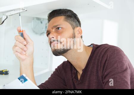 man with screwdriver installing shelf Stock Photo