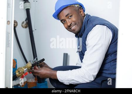 african male plumber fixing sink pipe in kitchen Stock Photo