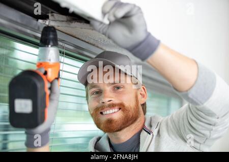 handyman using a cordless screwdriver to install a window Stock Photo