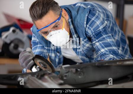 coachbuilder grinding a car part Stock Photo