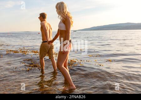 Couple holding hands and wading in the sea in the evening Stock Photo