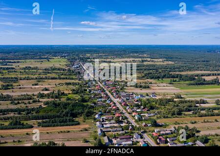 Aerial view of village surrounded by agricultural fields under blue sky idyllic view