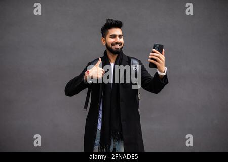 Happy friendly hipster guy enjoying video conversation outside. Young man in casual talking through video call on mobile phone. Nice phone talk concep Stock Photo